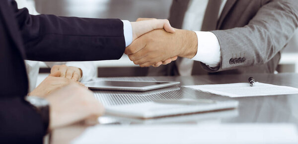 Handshake as successful negotiation ending, close-up. Unknown business people shaking hands after contract signing in modern office