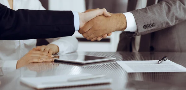 Handshake as successful negotiation ending, close-up. Unknown business people shaking hands after contract signing in modern office