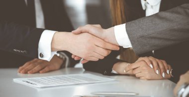 Bilinmeyen işadamı, modern ofiste iş arkadaşı ya da ortağıyla el sıkışıyor. Toplantıda iş adamları grubu