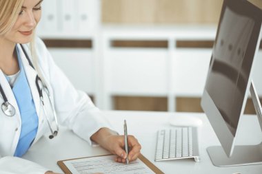 İş yerindeki bilinmeyen kadın-doktor klinikte ilaç geçmişi formunu dolduruyor, panonun yakın çekimini yapıyor.