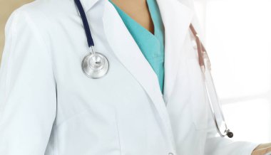 Güneşli klinikte steteskopla dikilen kimliği belirsiz kadın doktor, yakın plan.