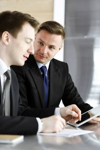 Empresario que usa tableta y trabaja junto con su colega o socio en el escritorio de cristal en la oficina moderna. Gente de negocios desconocida en la reunión. Trabajo en equipo y concepto de asociación — Foto de Stock