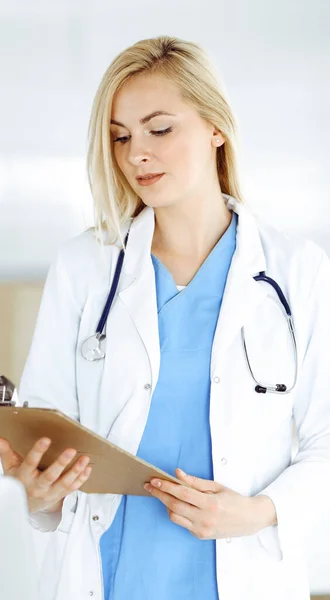 Mujer-médico de pie en el hospital o clínica y llenar el formulario de registro de la historia de la medicación. Datos y mejor servicio en medicina y salud — Foto de Stock