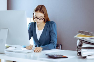 Muhasebeci mali durumu kontrol ediyor ya da vergi formları için hesap makinesi geliri ile sayıyor, eller yakın çekim. Ofisteki masada oturan ve çalışan bir iş kadını. Denetim kavramı