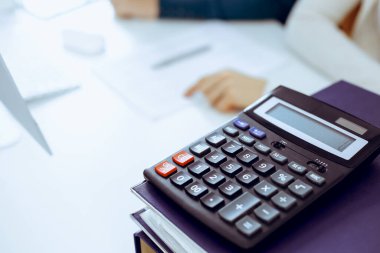 Hesap makinesi ve kağıtlar iş kadını ya da ofisteki büroda çalışan muhasebeci tarafından incelenmeyi bekliyor. İç Denetim ve vergi kavramı