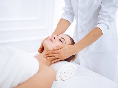 Genç ve sarışın kadın spa salonunda yüz masajından zevk alıyor. Güzellik konsepti