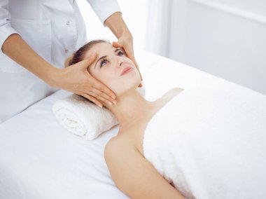 Genç ve sarışın kadın spa salonunda yüz masajından zevk alıyor. Güzellik konsepti