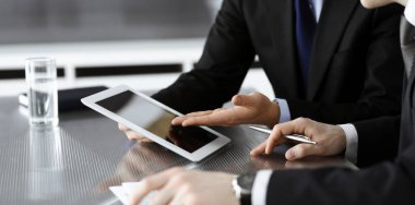 Bilinmeyen işadamları tablet bilgisayar kullanıyor ve modern ofisteki cam masada birlikte çalışıyorlar. Yakın plan. Takım çalışması ve ortaklık kavramı