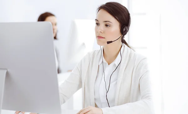 Call center. Casual dressed woman sitting in headset at customer service office. Group of operators at work. Business concept — Stock Photo, Image