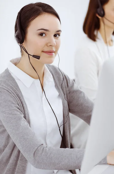 Τηλεφωνικό κέντρο. Casual ντυμένη γυναίκα που εργάζεται σε ακουστικά με διάφορους συναδέλφους στο γραφείο. Επιχειρηματική έννοια — Φωτογραφία Αρχείου