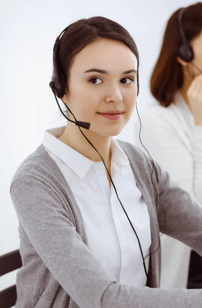 Τηλεφωνικό κέντρο. Casual ντυμένη γυναίκα που εργάζεται σε ακουστικά με διάφορους συναδέλφους στο γραφείο. Επιχειρηματική έννοια — Φωτογραφία Αρχείου