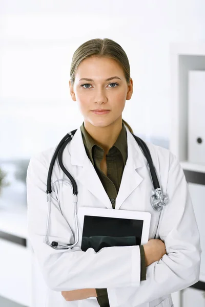 Žena-doktorka stojí a dívá se do kamery. Perfektní lékařská služba na klinice. Léky a zdravotní péče — Stock fotografie