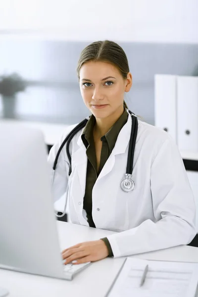 Mujer-médico escribiendo en la computadora PC mientras está sentado en el escritorio en la oficina del hospital. Médico trabajando. Datos en medicina y asistencia sanitaria — Foto de Stock