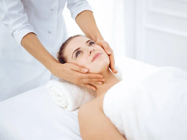 Mladá a blonďatá žena si užívá masáž obličeje v lázeňském salonu. Krása konceptu — Stock fotografie