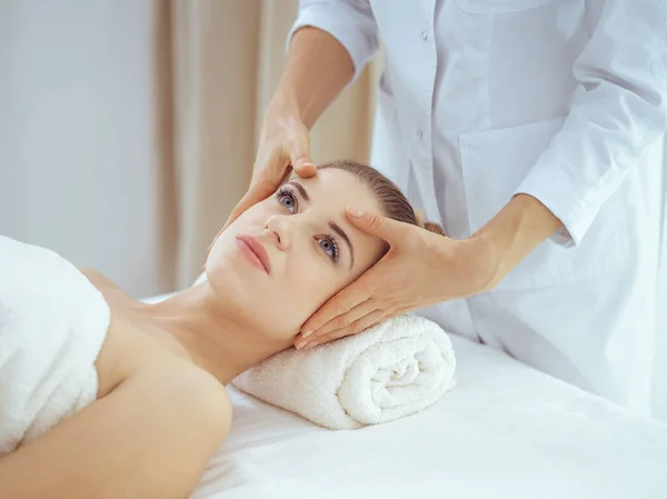 Giovane e bionda donna godendo massaggio facciale nel salone spa. Concetto bellezza — Foto Stock