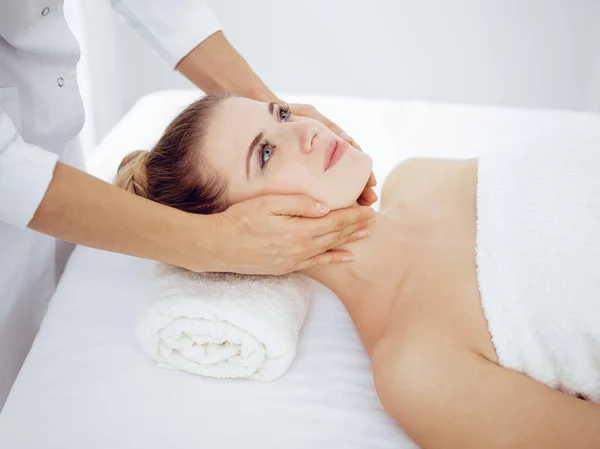 Mujer joven y rubia disfrutando de masajes faciales en el salón de spa. Concepto de belleza — Foto de Stock