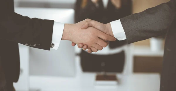 Unknown businessman shaking hands with his colleague or partner while standing straight in modern office, close-up. Business people group at meeting — Stock Photo, Image