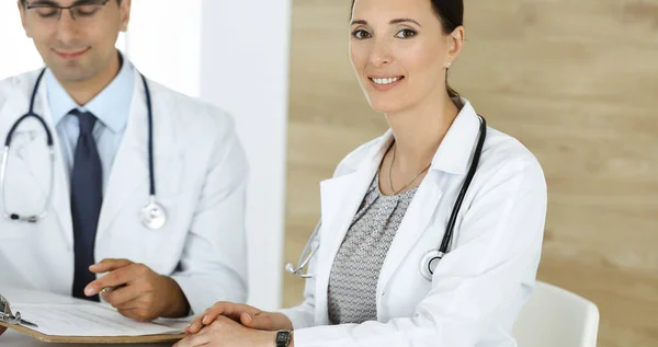 Two doctors discussing treatment problems while sitting at the desk in hospital office. Data in medicine and health care concept