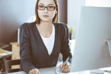 Muhasebeci mali durumu kontrol ediyor ya da vergi formları için hesap makinesi geliri ile sayıyor, eller yakın çekim. Ofisteki masada oturan ve çalışan bir iş kadını. Denetim kavramı