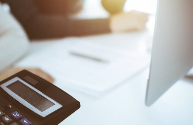 Hesap makinesi ve kağıtlar iş kadını ya da ofisteki büroda çalışan muhasebeci tarafından incelenmeyi bekliyor. İç Denetim ve vergi kavramı