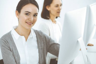 İş kadını, çalışan iş arkadaşlarının arka planına bakıyor. Ofis hayatı konsepti, vesikalık