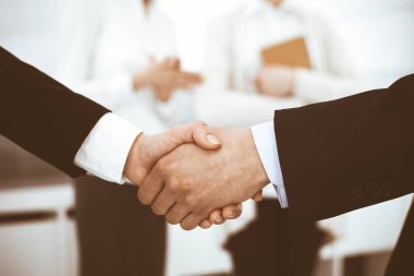 İş adamı ve kadın arka planda iş arkadaşlarıyla tokalaşıyor. Ofiste tokalaşırken. İş hayatında başarı kavramı