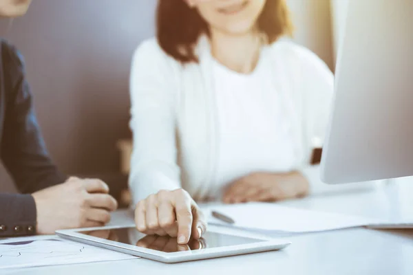 Geschäftsfrau zeigt auf den Bildschirm des Tablet-Computers, während sie ihrer Kollegin eine Präsentation gibt. Gruppe von Geschäftsleuten, die am Schreibtisch im Büro arbeiten. Teamwork-Konzept — Stockfoto