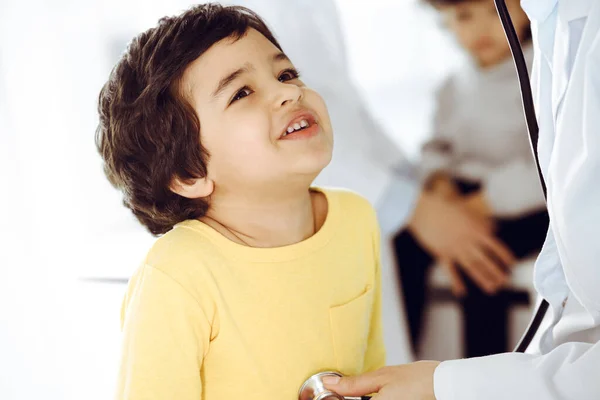 Mujer-médico examinando a un niño paciente por estetoscopio. Lindo chico árabe en la cita con el médico. Medicina ayuda concepto — Foto de Stock