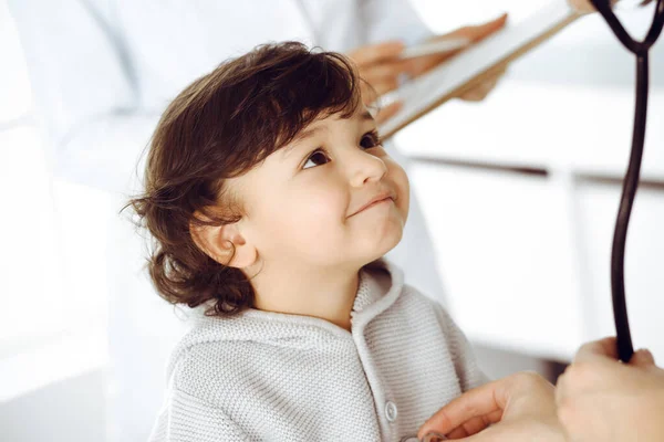 Woman-doctor examining a child patient by stethoscope. Cute arab toddler at physician appointment. Medicine concept — Stock Photo, Image