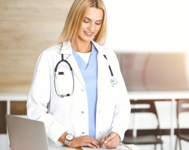 Doktor kadın, Sunny Hastanesi 'nde pano kullanırken ilaç kayıtlarını ve sınav sonuçlarını kontrol ediyor. Tıp ve sağlık hizmetleri kavramı