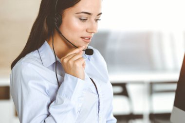 Esmer kadın müşteri hizmetleri temsilcisi kulaklık ve danışman müşteriler kullanıyor. Çağrı merkezi