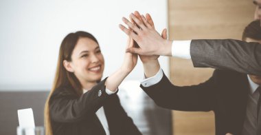 Bilinmeyen iş adamları modern ofiste el ele tutuşuyor. İş adamları ve kadınlar elleriyle bir takım olarak daire çiziyorlar, yakın plan.