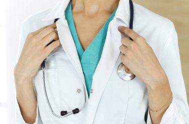 Klinikte steteskopla duran kimliği belirsiz kadın doktor, yakın plan. Tıp konsepti