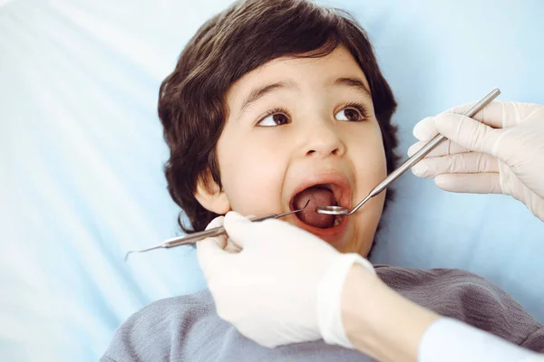 Cute arab boy sitting at dental chair with open mouth during oral checking up with doctor. Visiting dentist office. Stomatology concept — Stock Photo, Image