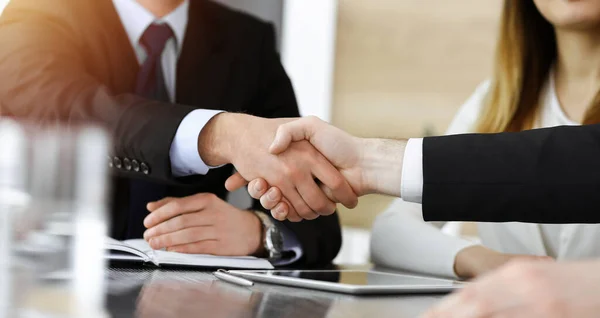 Zakenman schudt handen met zijn collega boven het glazen bureau in zonnig modern kantoor, close-up. Onbekende zakenmensen bij vergadering — Stockfoto