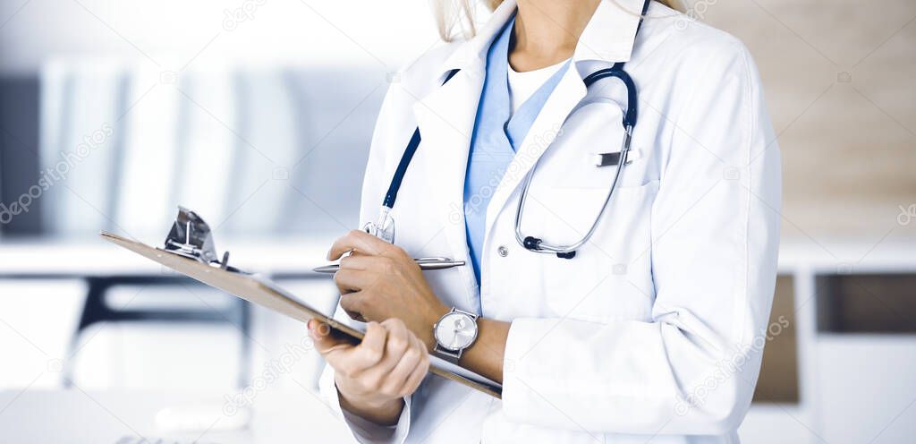 Unknown woman-doctor at work in clinic. Female physician controls medication history record and medical exam results, close-up. Medicine concept