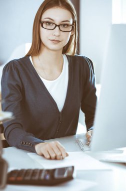 Muhasebeci mali durumu kontrol ediyor ya da vergi formları için hesap makinesi geliri ile sayıyor, eller yakın çekim. Ofisteki masada oturan ve çalışan bir iş kadını. Denetim kavramı