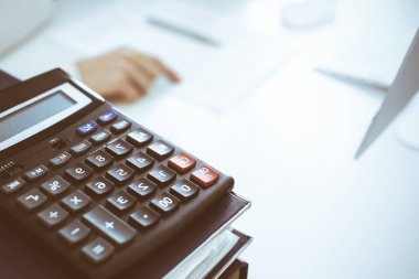 Hesap makinesi ve kağıtlar iş kadını ya da ofisteki büroda çalışan muhasebeci tarafından incelenmeyi bekliyor. İç Denetim ve vergi kavramı