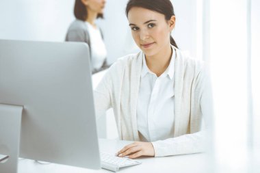 Ofiste bilgisayarla çalışan sıradan giyinmiş bir iş kadını. İş yerinde avukat ya da muhasebeci