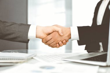 Bilinmeyen çeşitli iş adamları ofis masasındaki toplantıyı bitirmek için el sıkışıyorlar, yakın plan. El sıkışma kavramı