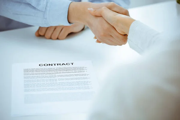 Случайно одетые бизнесмен и женщина пожимают друг другу руки после подписания контракта в офисе белого цвета. Понятие рукопожатия — стоковое фото