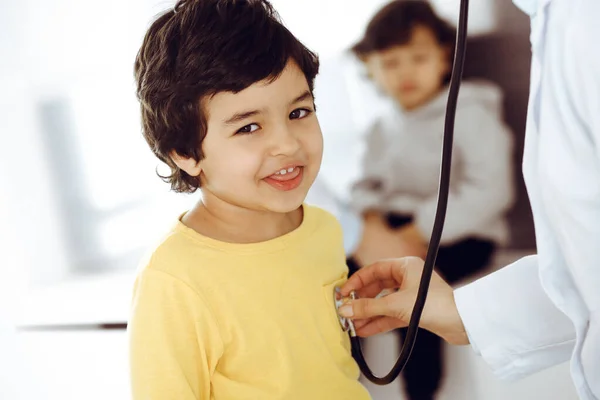 Ärztin untersucht eine Kinderpatientin mit dem Stethoskop. Netter arabischer Junge beim Arzttermin. Medikamentenhilfekonzept — Stockfoto