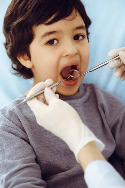Kleiner arabischer Junge sitzt mit offenem Mund am Zahnarztstuhl während der mündlichen Untersuchung beim Zahnarzt. Stomatologisches Konzept — Stockfoto