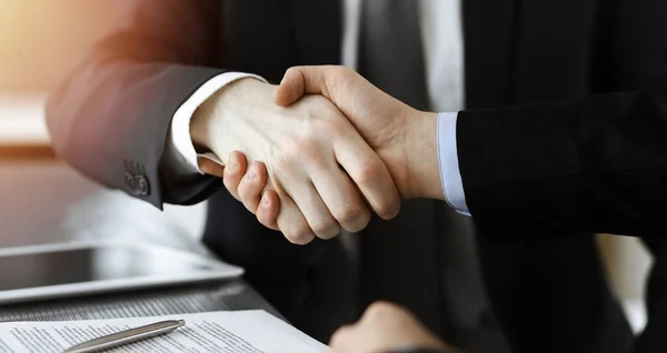 Zakenman schudt handen met zijn collega boven het glazen bureau in zonnig modern kantoor, close-up. Onbekende zakenmensen bij vergadering — Stockfoto