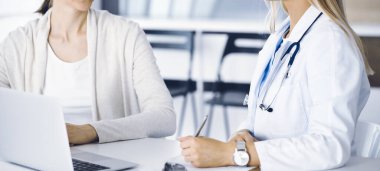 Bilinmeyen kadın doktor oturuyor ve kadın hastayla iletişim kuruyor. Doktor tıbbi geçmişi ve muayene sonuçlarını yakından kontrol ediyor. Sağlık hizmetleri kavramı