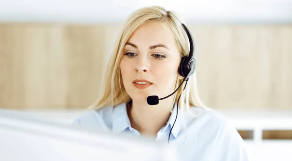 Blond affärskvinna sitter och kommuniceras med headset i call center kontor. Begreppet distansförsäljning företag eller hemmakontor yrke — Stockfoto