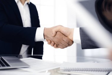 Bilinmeyen çeşitli iş adamları ofis masasındaki toplantıyı bitirmek için el sıkışıyorlar, yakın plan. El sıkışma kavramı