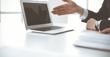 Bilinmeyen iş adamları modern ofisteki masada dizüstü bilgisayar kullanıyorlar. İş adamı ya da erkek girişimci meslektaşı ile birlikte çalışıyor. Takım çalışması ve ortaklık kavramı