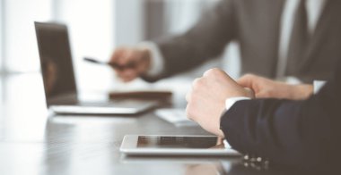 Bilinmeyen iş adamları ve kadınlar oturmuş, dizüstü bilgisayarlarını kullanıyorlar ve modern ofiste buluşmada soruları tartışıyorlar, yakın plan.