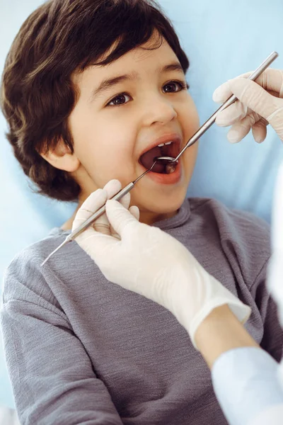 Kleiner arabischer Junge sitzt mit offenem Mund am Zahnarztstuhl während der mündlichen Untersuchung beim Zahnarzt. Stomatologisches Konzept — Stockfoto